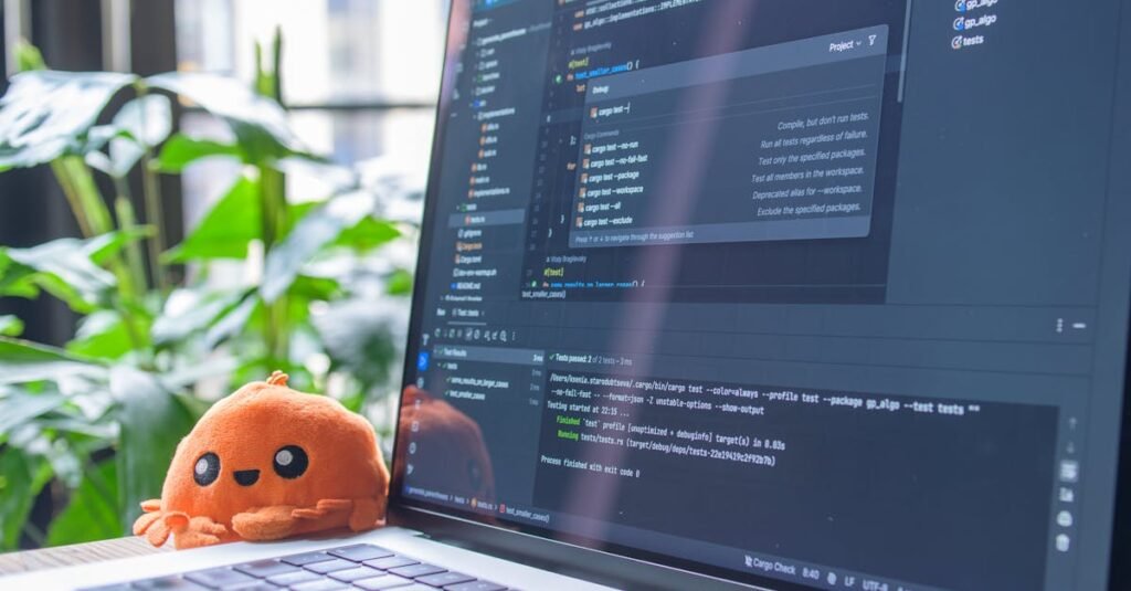 Open laptop with code editor displaying, next to an orange plush toy and green plants.