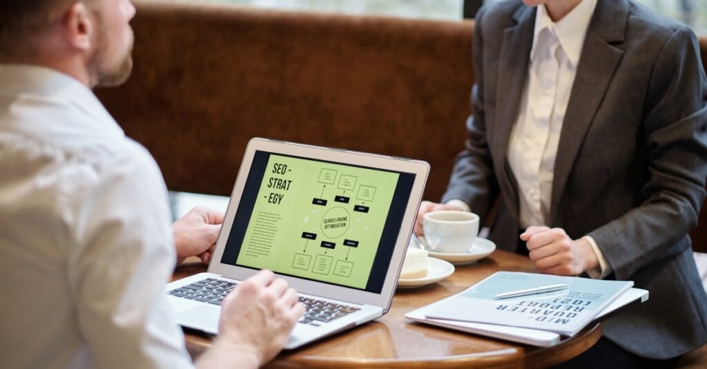 A man and woman engaged in a business meeting discussing SEO strategy in a cozy cafe setting.