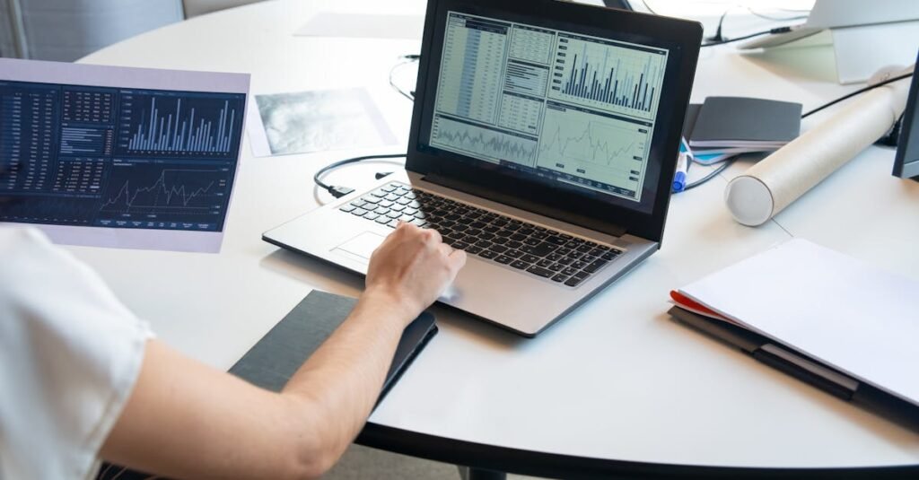 Business person evaluating financial charts on a laptop in a modern office setting.