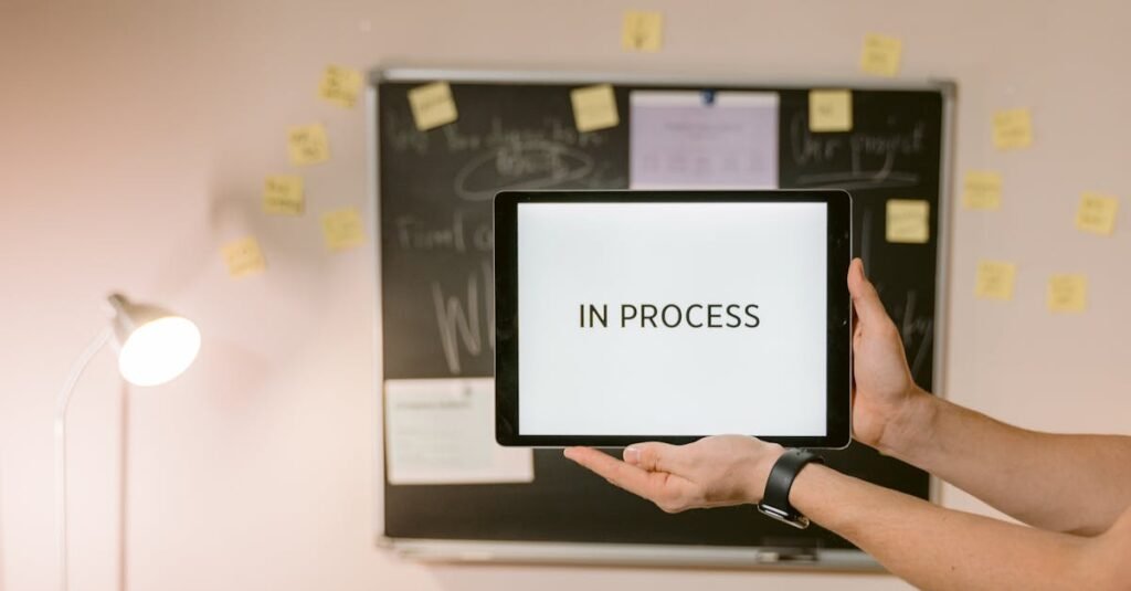 Tablet with 'In Process' text held in an office setting, under analytical review.