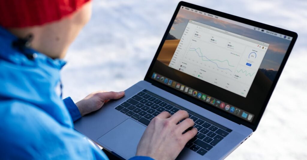 Person working on a laptop analyzing charts in an outdoor setting during winter.