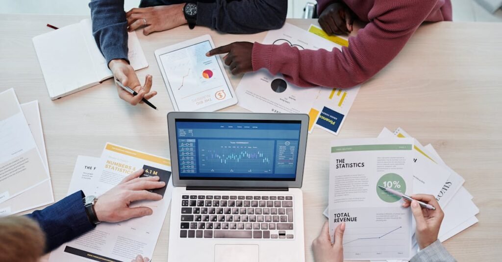 Top view of colleagues analyzing data on a digital device in an office setting.
